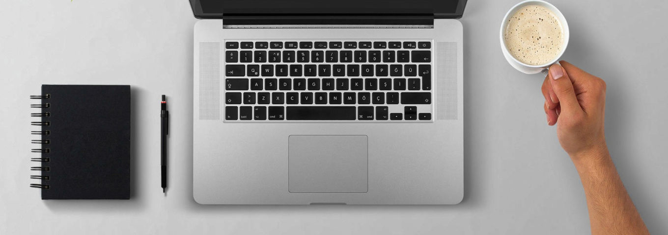 Labtoptastatur, Notizblock, Stift und eine Hand, die eine Tase Kaffe hält.